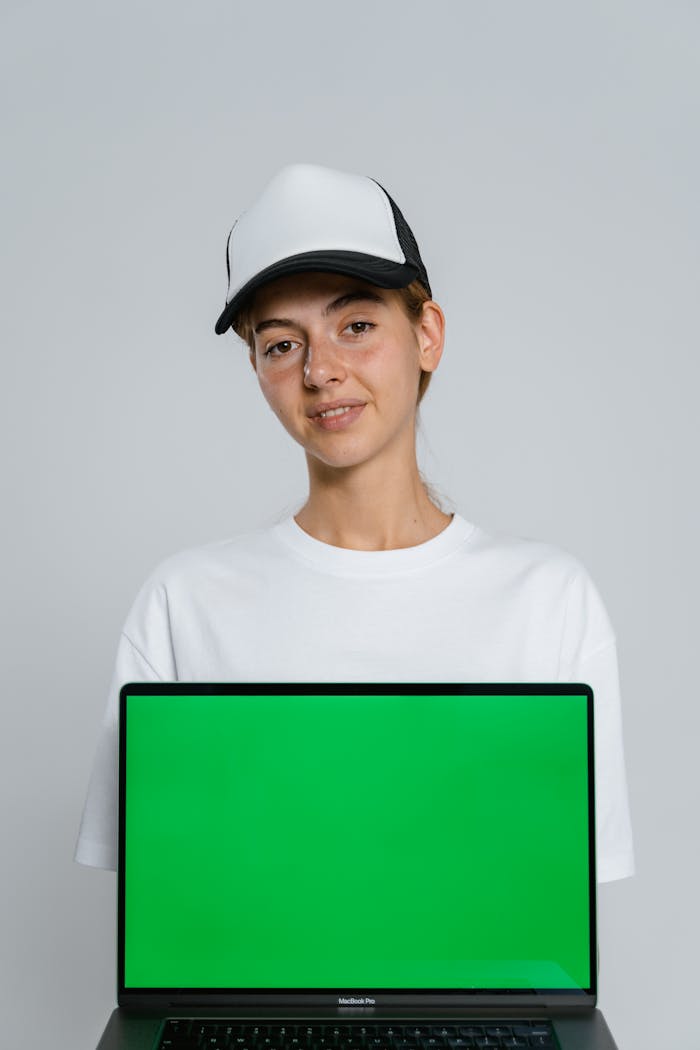 Services Studio portrait of a woman in casual wear holding a laptop with a green screen.